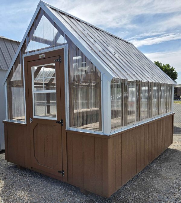8x12 greenhouse, 12/12 roof pitch, clear polycarbonate roof, barn style door with 2x3 window, 21" x 21" automatic louvre back vent door, 18" deep perimeter potting shelf, upper wall .8mm, smart panel base siding with pine cone solid stain.