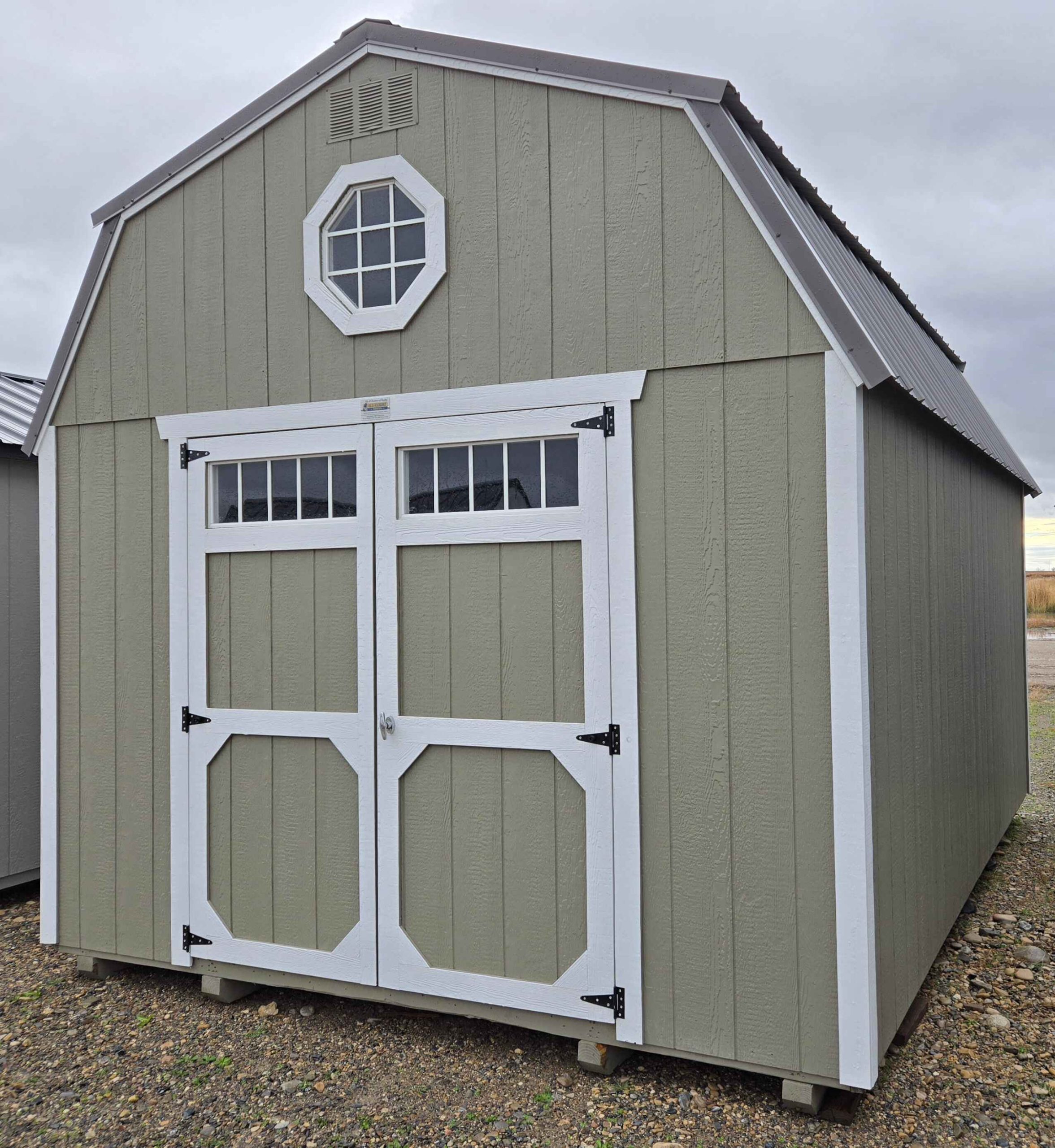 12x16 Lofted Barn, burnished slate metal roof, hardware walls, barn white trim, 7ft tall walls, double barn doors with windows, two 4ft lofts, octagon window in front loft, shelves, wood floor, 60psf snow load, engineer certified.
